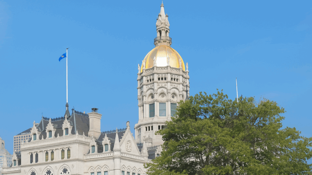 The Connecticut State Capitol in Hartford, featuring its gold dome and Gothic Revival details beneath a clear blue sky.